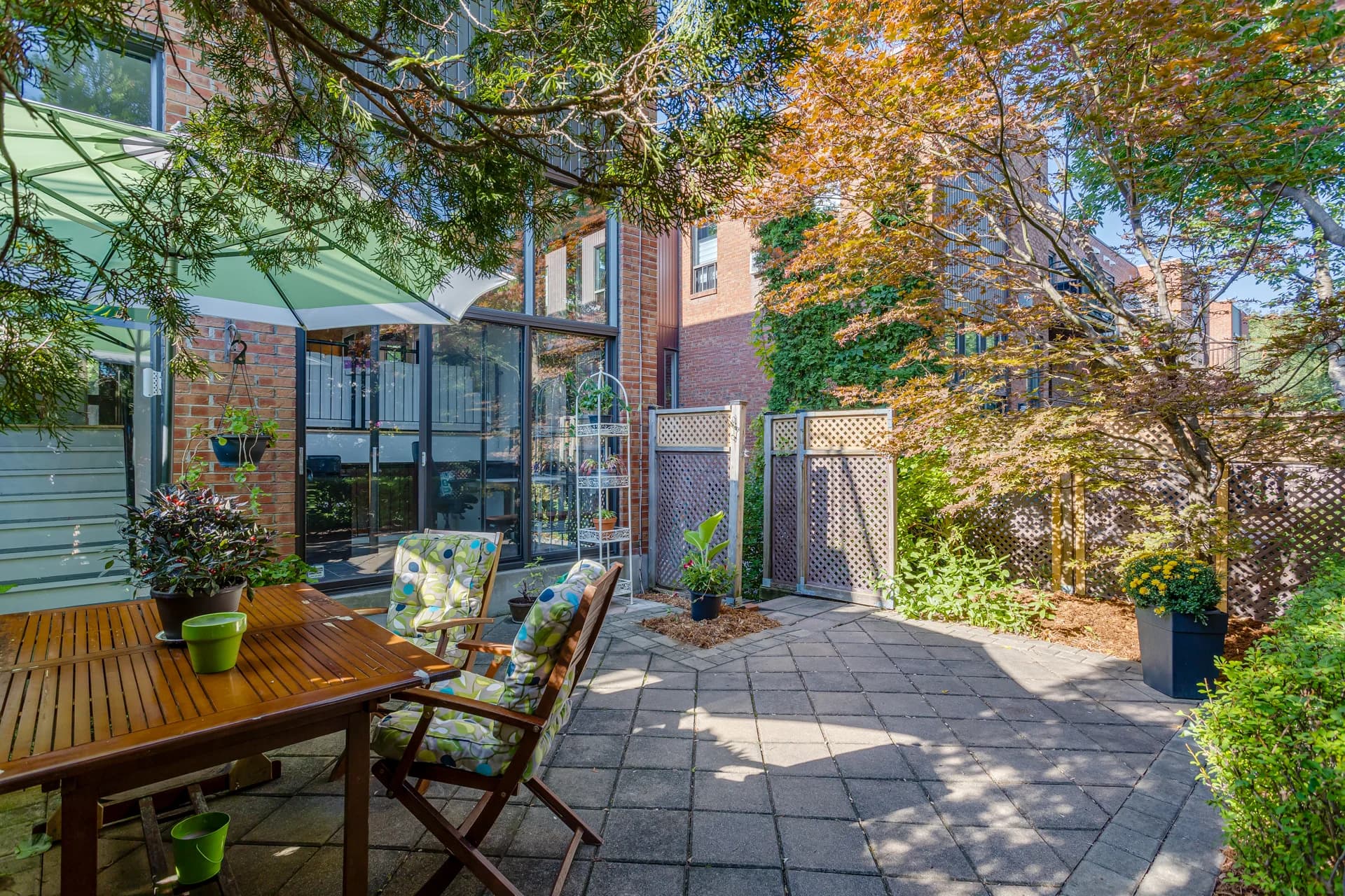 Cour avec terrasse pavée et arbres près d'une façade de brique