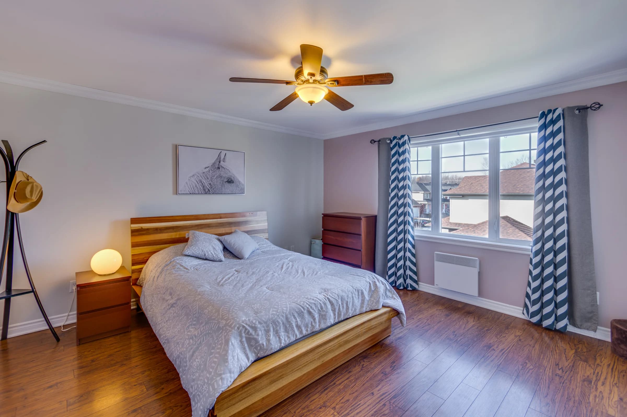 Chambre avec lit double, plancher en bois et grandes fenêtres