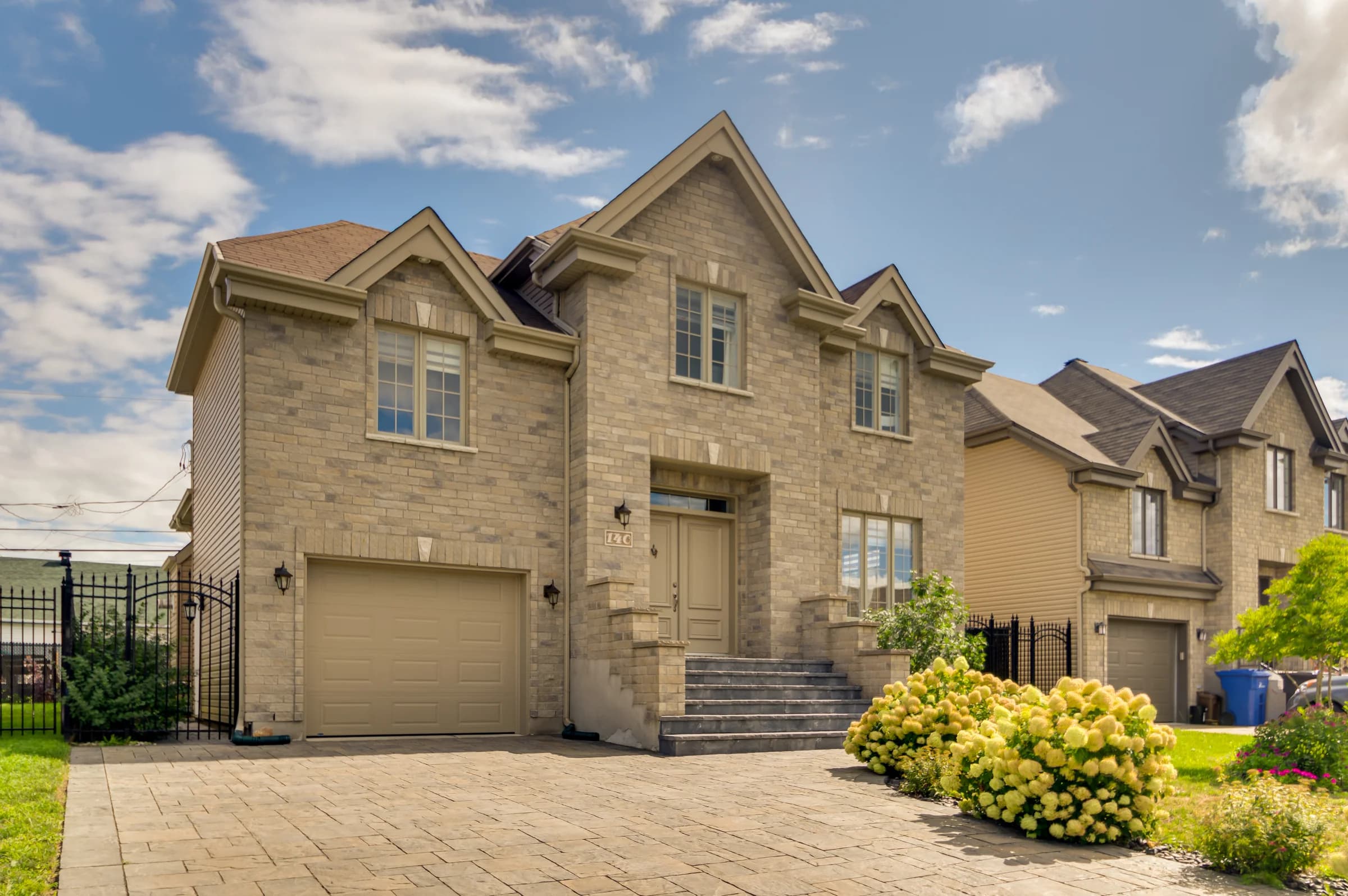 Façade en pierre avec garage double et entrée pavée