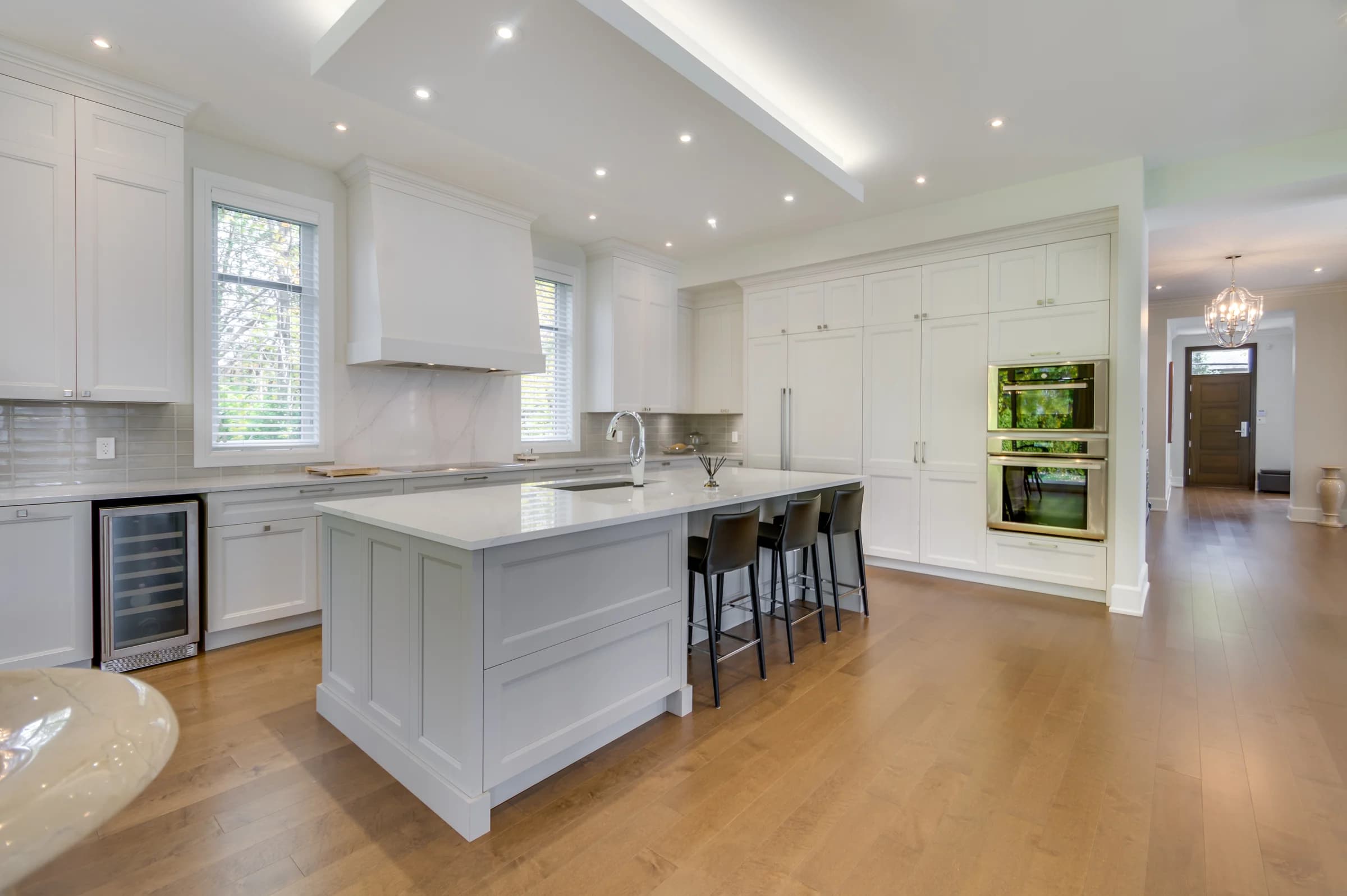 Cuisine blanche lumineuse avec grand îlot et tabourets