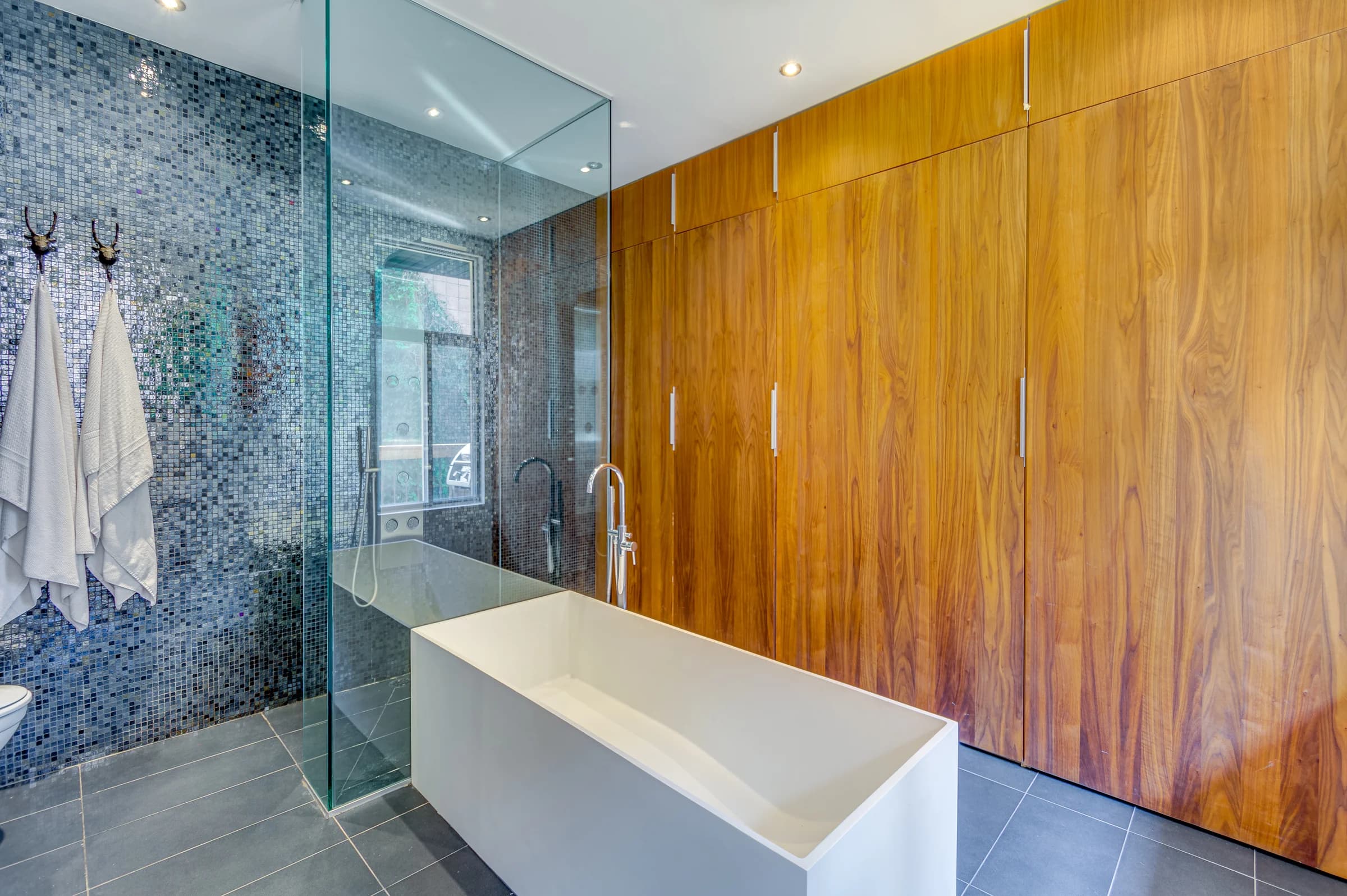 Salle de bain avec baignoire rectangulaire, mosaïque bleue et mur en bois