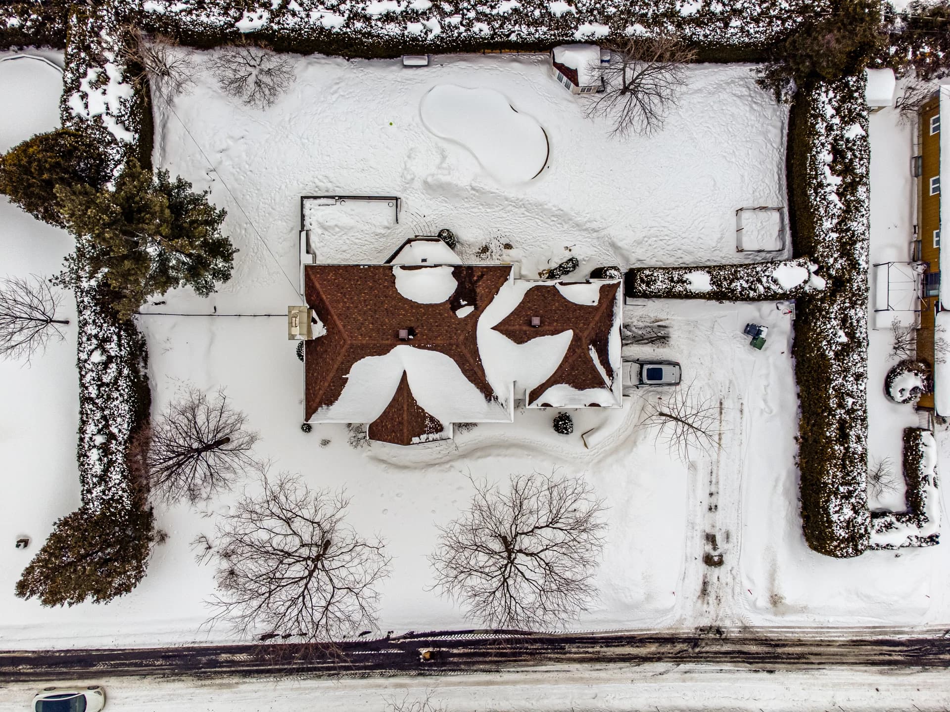 Overhead drone view of a house and its snow-covered grounds
